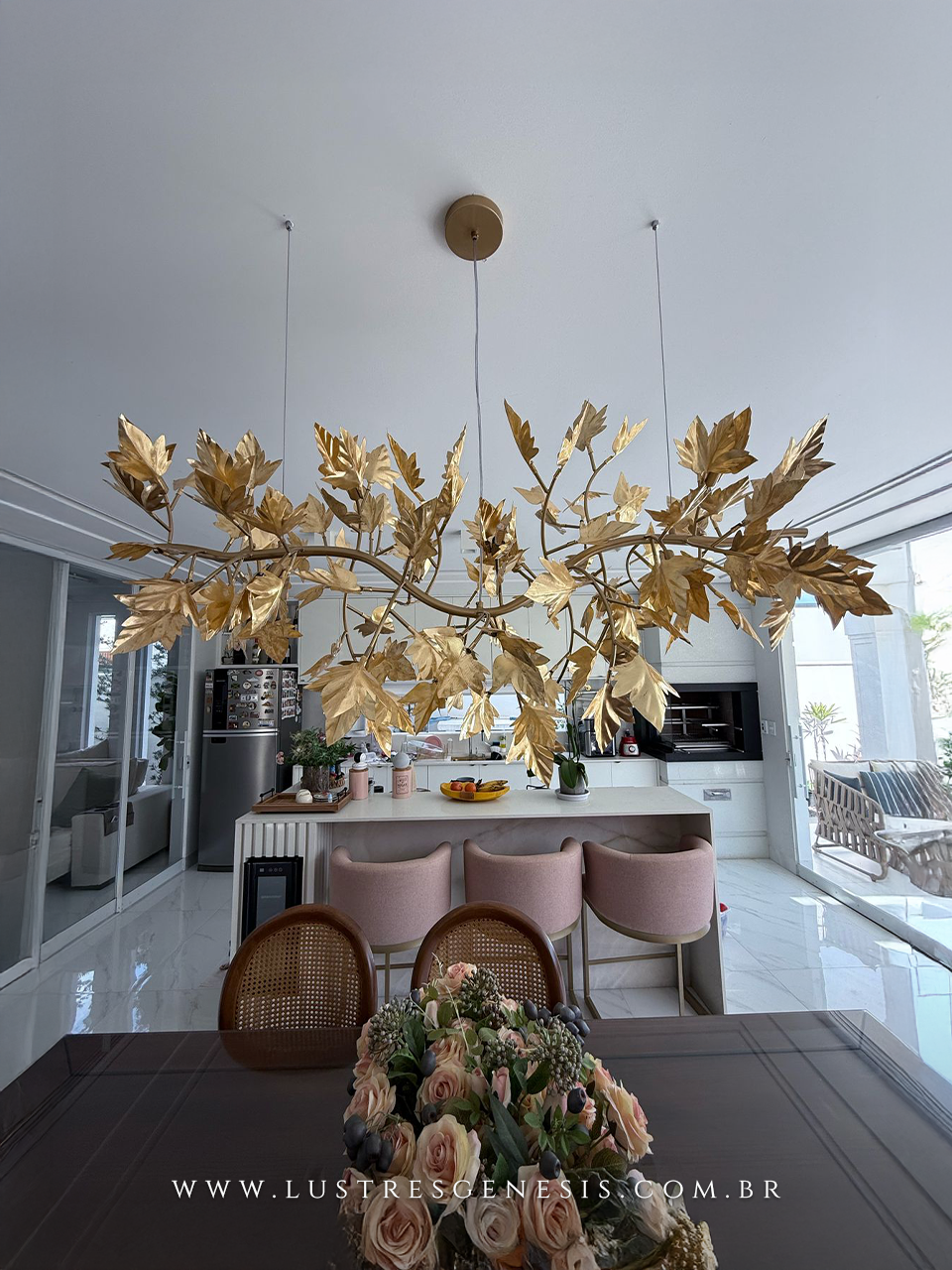 Lustre pendente folhado a ouro em formato de pétalas, instalado acima da mesa de jantar em ambiente moderno e sofisticado.